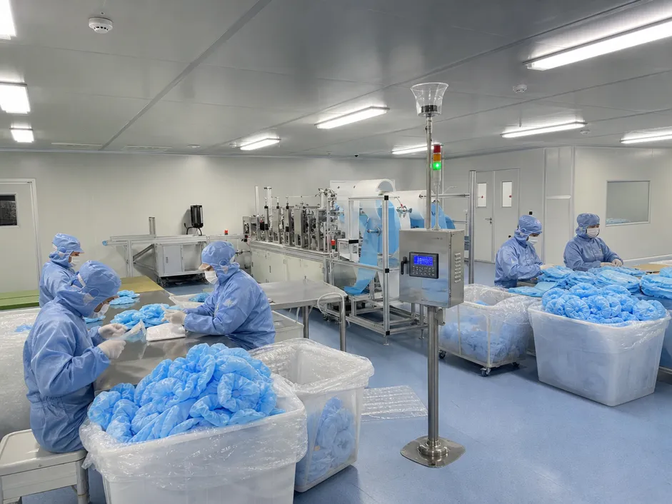ISO 8 cleanroom production environment for bouffant medical caps with gowned operators and particle monitoring