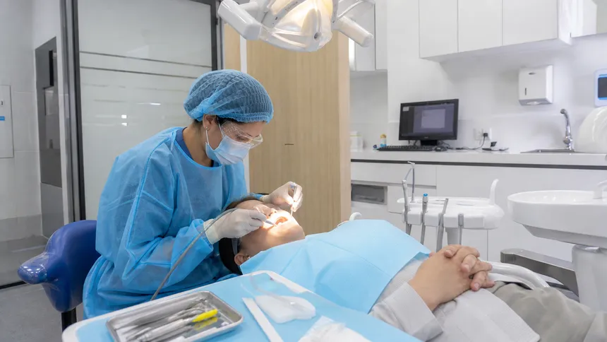 Dental hygienist wearing bouffant cap and PPE during a procedure