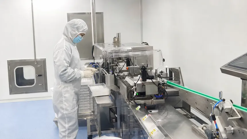Pharmaceutical cleanroom worker in full gowning protocol including bouffant cap