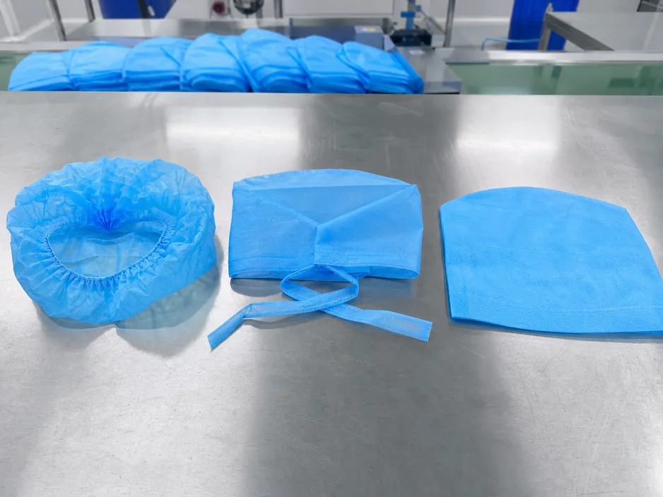 Three variants of disposable medical caps — bouffant, surgical tie-back, and standard flat cap — displayed on a cleanroom production surface