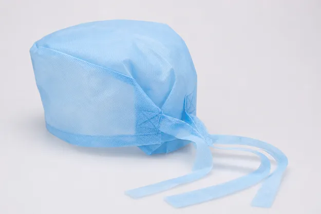 Surgical tie-back medical cap with reinforced tie attachment points in spunbond nonwoven