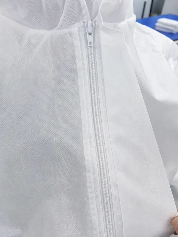 Close-up of ultrasonic-welded seam and front zipper with adhesive flap cover on disposable medical protective clothing