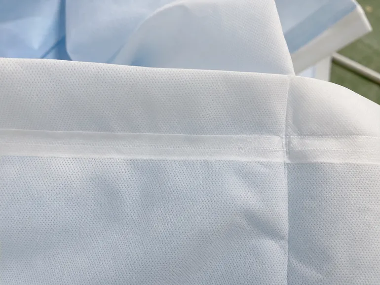 Close-up of ultrasonic welded seam on disposable medical protective clothing showing fused nonwoven layers with no needle holes