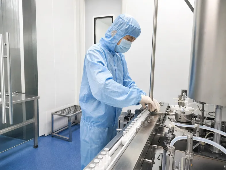 Pharmaceutical cleanroom technician wearing medical-grade protective coverall during production