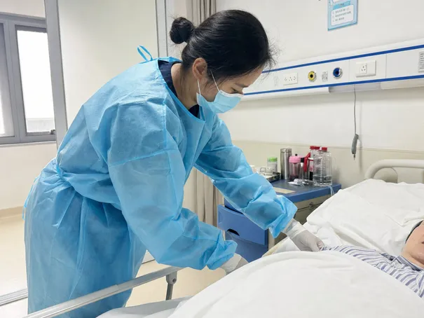 Healthcare worker wearing disposable isolation gown during patient contact in hospital ward