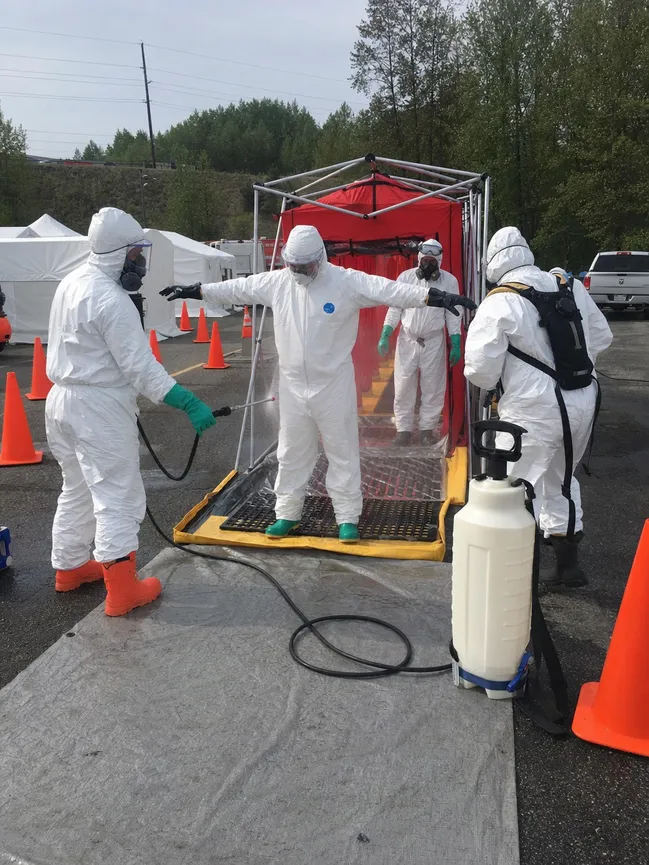 First responders in protective coveralls during hazmat decontamination operation