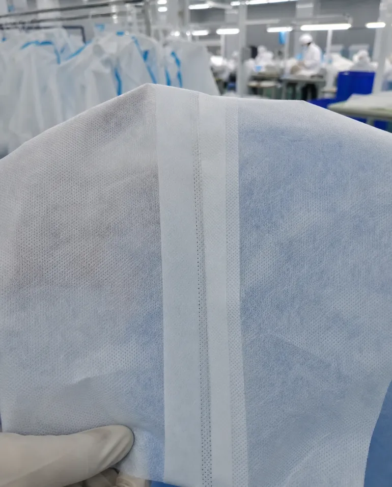Close-up of ultrasonic-welded seam on medical protective coverall showing fused nonwoven layers without needle holes